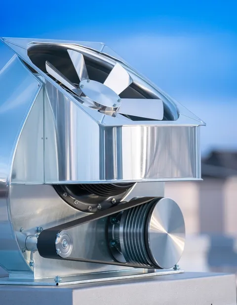 Technician cleaning a rooftop exhaust fan after hours